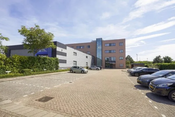 Kantoorgebouw aan de Laan van 's-Gravenmade met parkeerplaatsen op de voorgrond op een zonnige dag.